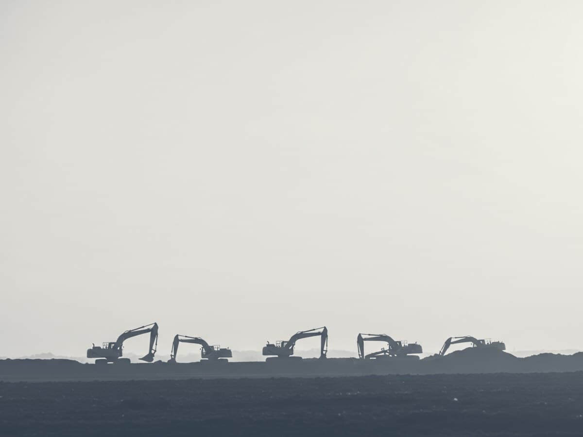 Duotone graphic of excavators silhouetted on a graded-site horizon.